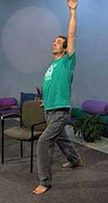 standing man holds chair while reaching other arm towards sky in adapted warrior pose